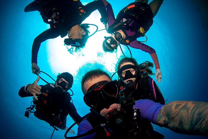 Five Divemaster trainees and divers posing together underwater